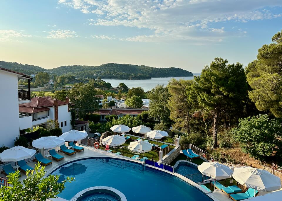 View over a hotel swimming pool over lush foliage to the sea.