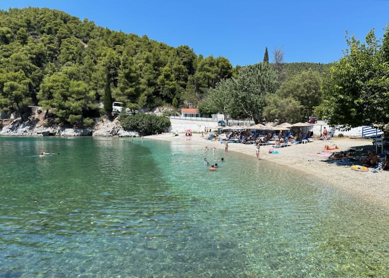 Distant view of a beach taverna and sun beds on a beach on the island of Skopelos