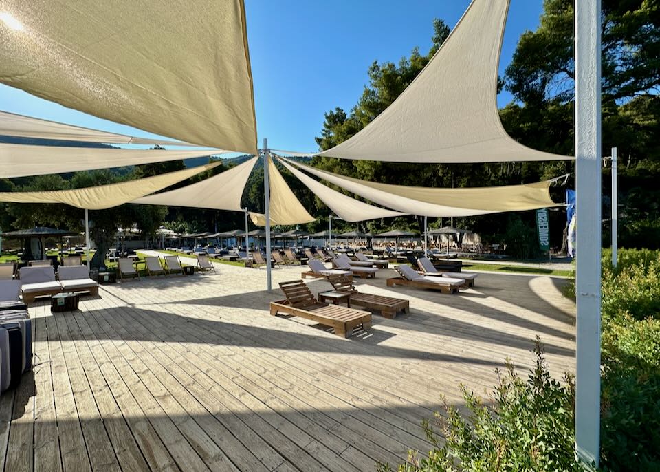 Rows of shaded sun beds on a wooden platform.