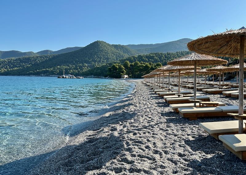 Rows of sunbeds almost touching the water on a beautiful pebble beach.