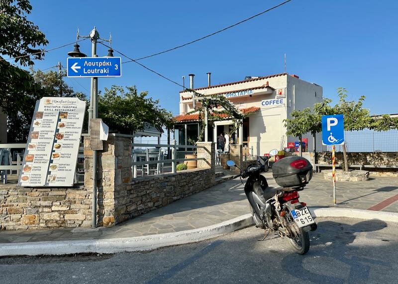 Motorcycle parked in front of a Greek taverna overlooking the sea