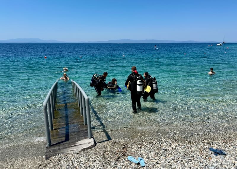 instructor and students in a scuba diving lesson in shallow blue water