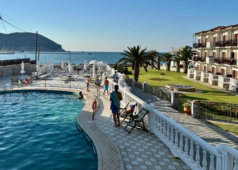 Hotel swimming pool set next to a green lawn and overlooking the sea