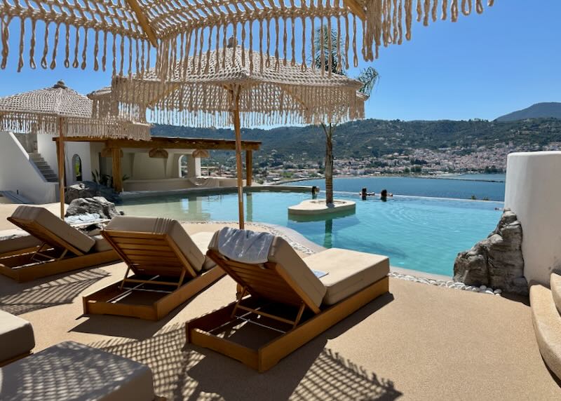 Two people lounge in a hotel infinity pool overlooking the sea