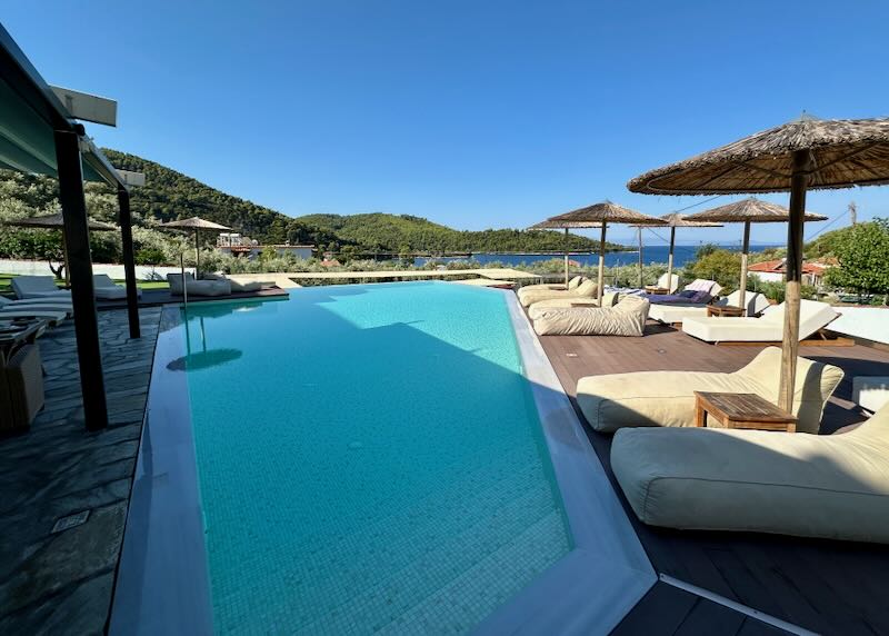 Free-form swimming pool surrounded by puffy shaded sun beds