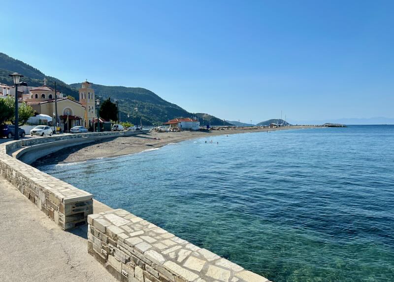 View along a seafront road toward a Greek Orthodox church on the water