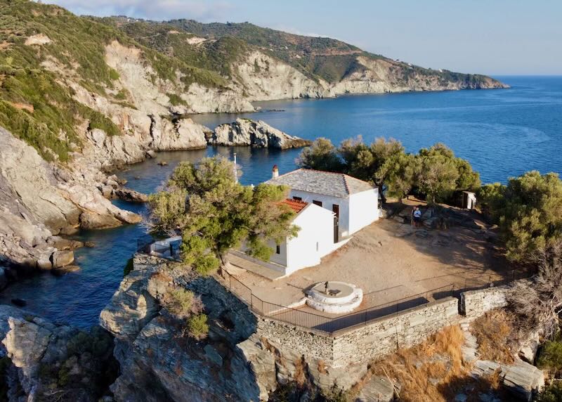 View of a white Greek chapel on a cliff, from above