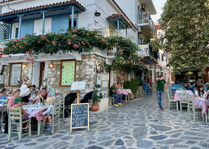 Cafe tables on a cobblestone path in a Greek village