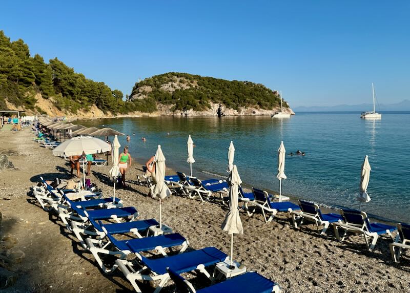 Sandy brown beach lined with blue beach lounge chairs