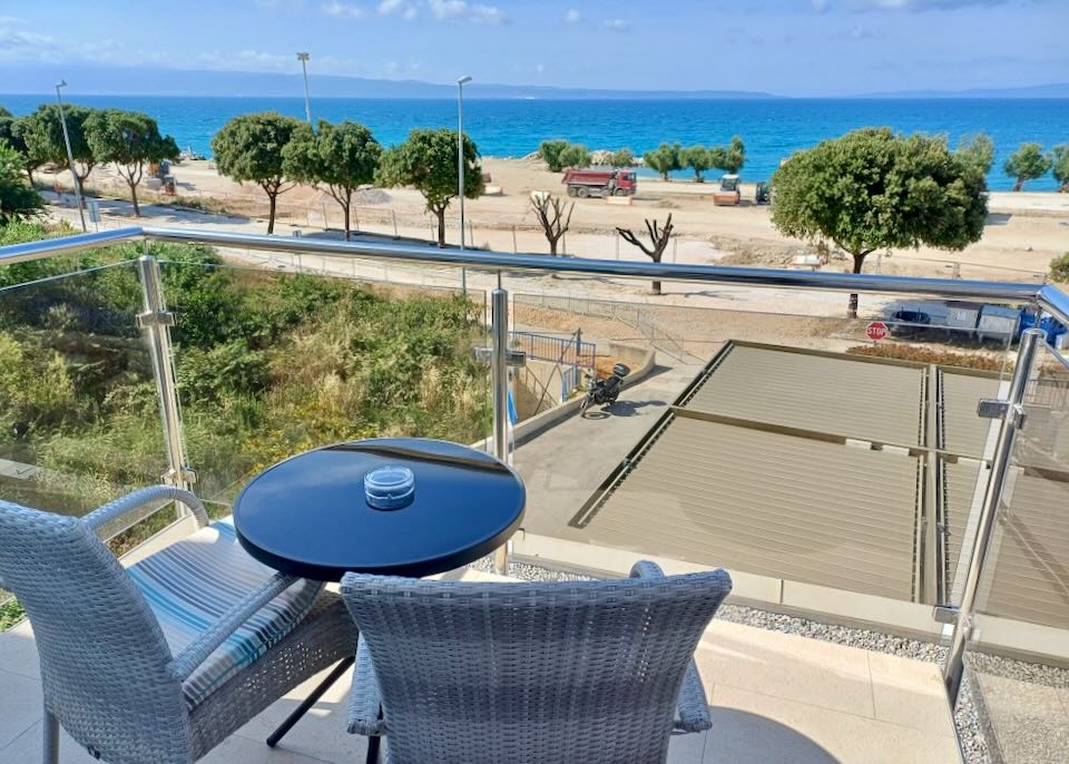 Chairs sit on a balcony and overlook the sea.