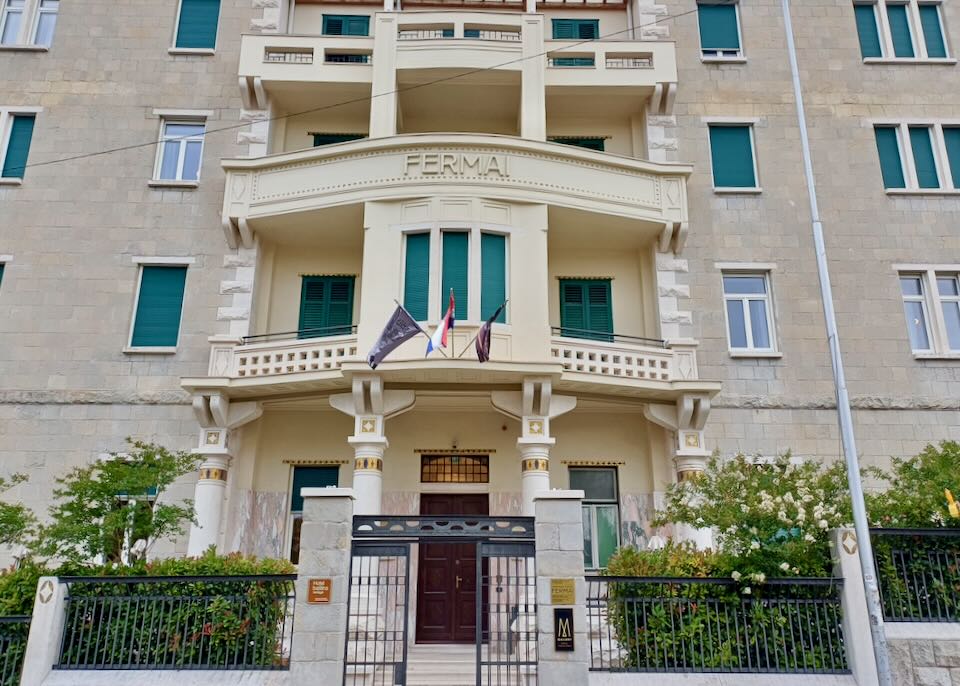 A tall cream-colored stone building with green shutters.