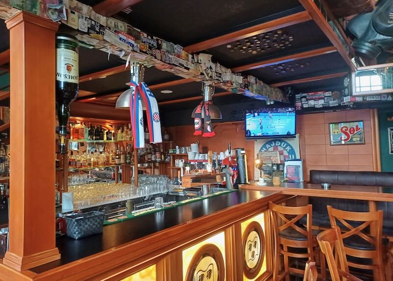 A wood bar with a tv showing a sport event.