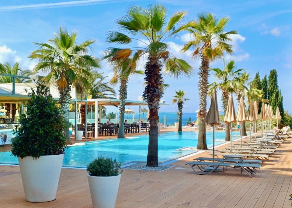 A blue pool has lounge chairs set around it.