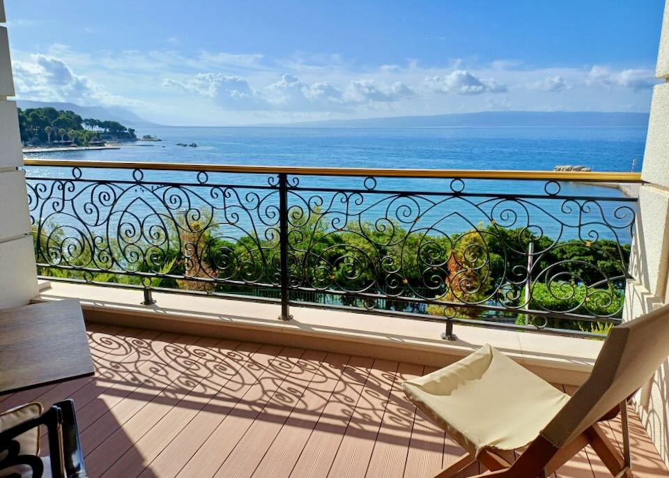 A balcony with black rounded iron fencing with a view of blue water.