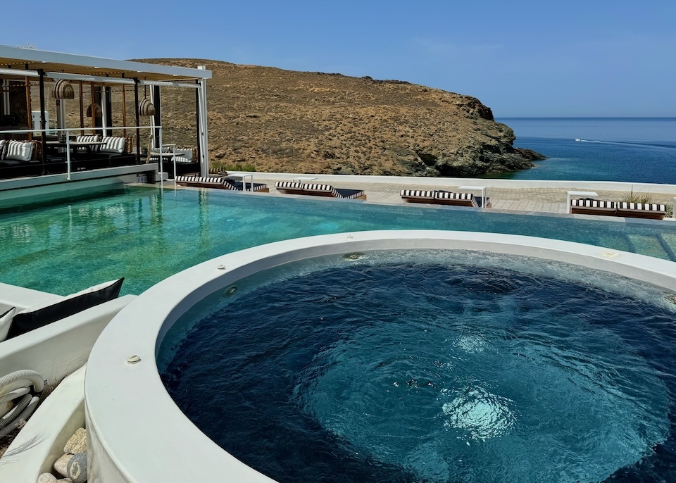 A jacuzzi set behind an infinity pool with a view to the sea at Semeli Coast near Merchia Beach in Mykonos.