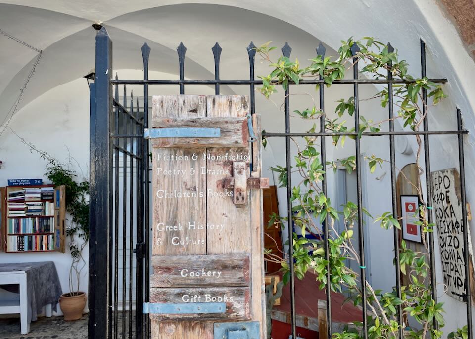 Rustic bookstore sign hung on wrought-iron fencing.