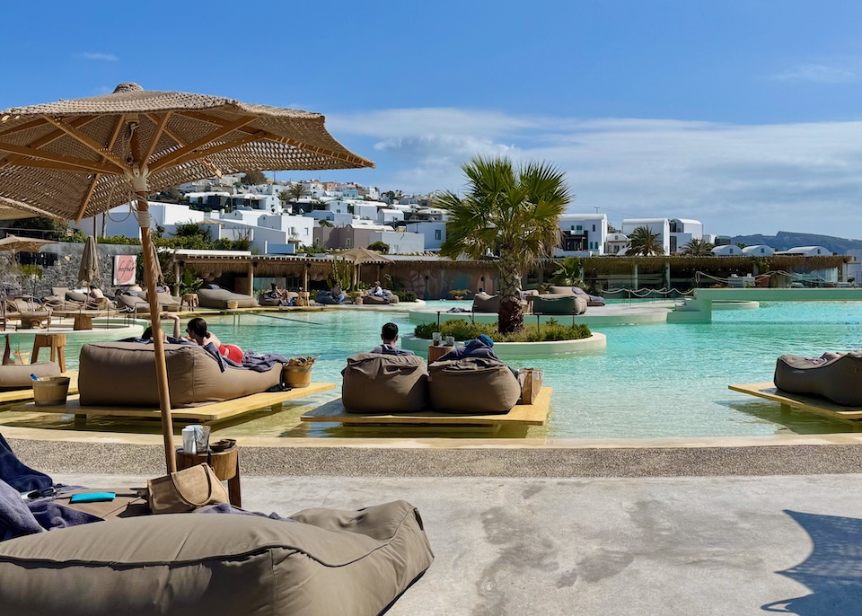 A lagoon-inspired pool with sunbeds perched in the shallow water and more ringing the outside edge at Andronis Arcadia in Oia.