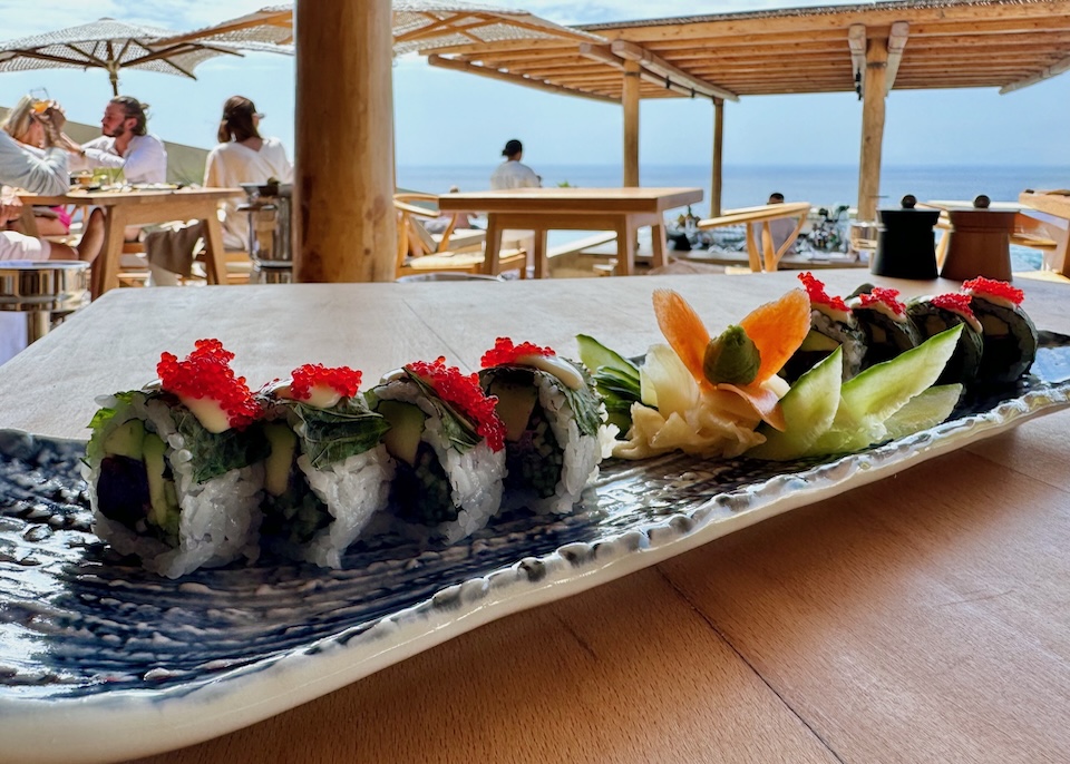 A colorful sushi roll on a wooden table with sea views at Andronis Arcadia in Oia.
