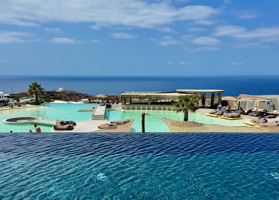 View of the sea and a lagoon-style pool from a higher up infinity pool at Andronis Arcadia in Oia, Santorini.