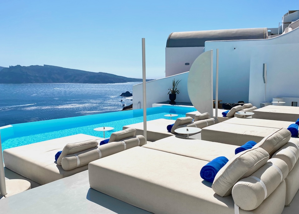 An infinity pool with two rows of double sized sunbeds facing over the caldera at Saint hotel in Oia.