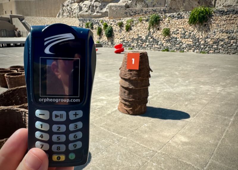 The photographer is holding up a handheld audio device that looks like an old mobile phone.