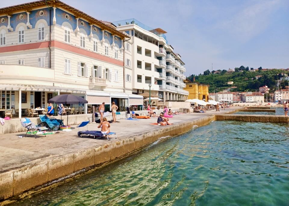 People sit in chairs sunbathing on a cement block by the sea.