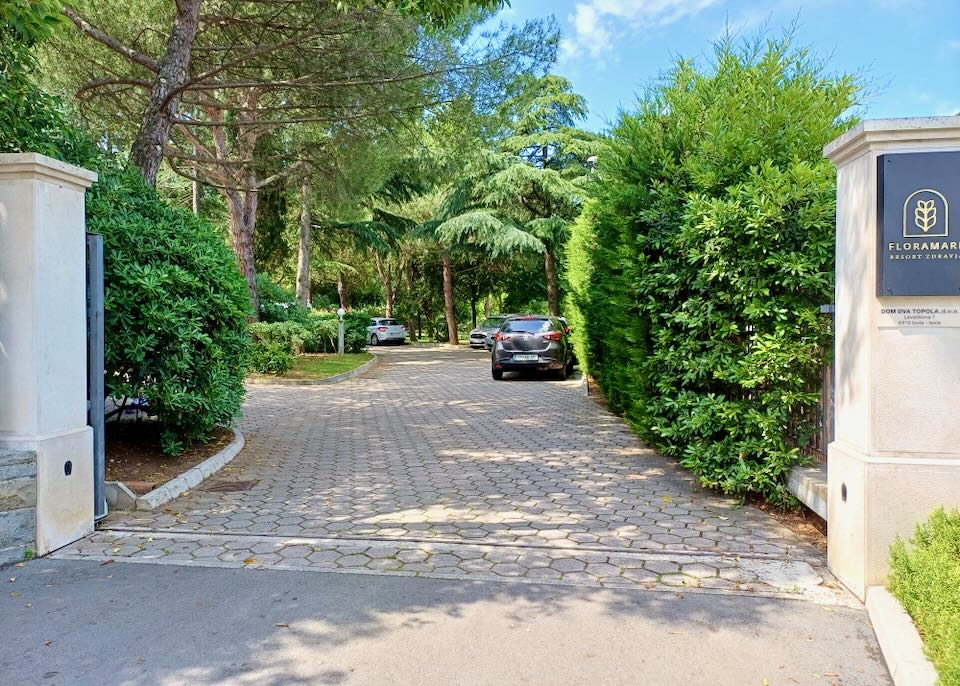 A gate opens to green trees and a hotel parking area.
