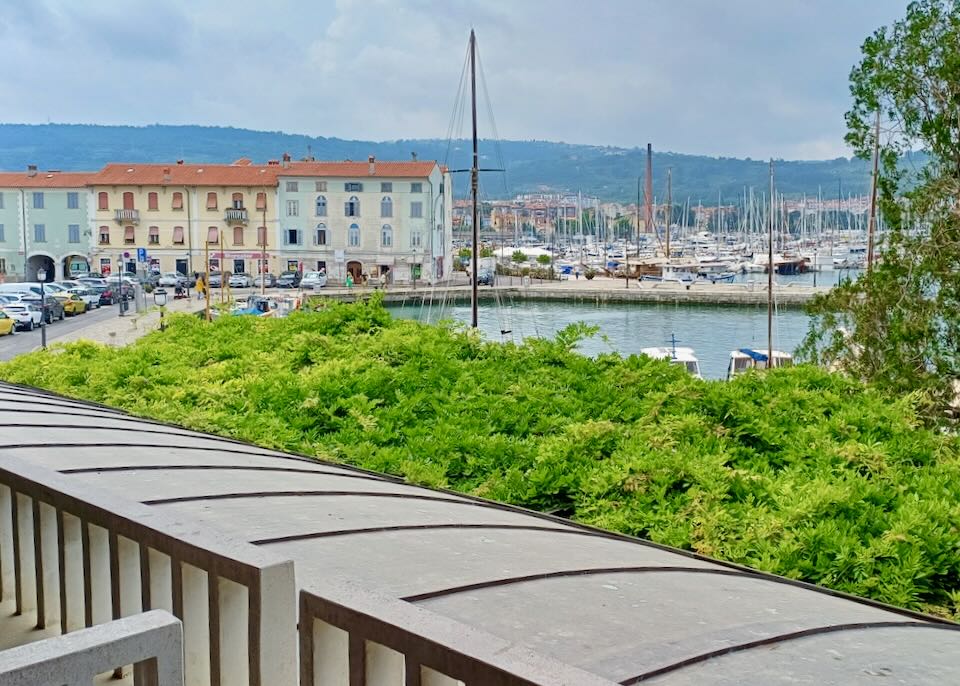 From a hotel balcony are views of a marina with pastel-colored buildings.