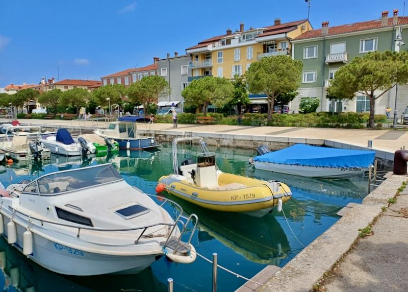 Small boats sit tied to a wall in a marina.