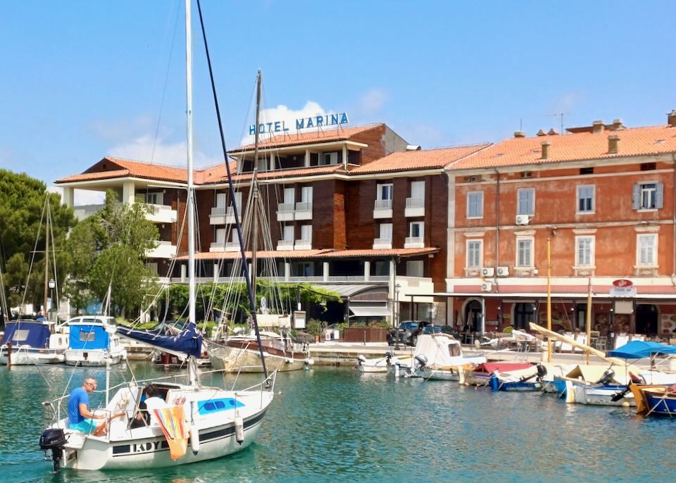 A man sits in a small boat drifting into a marina.