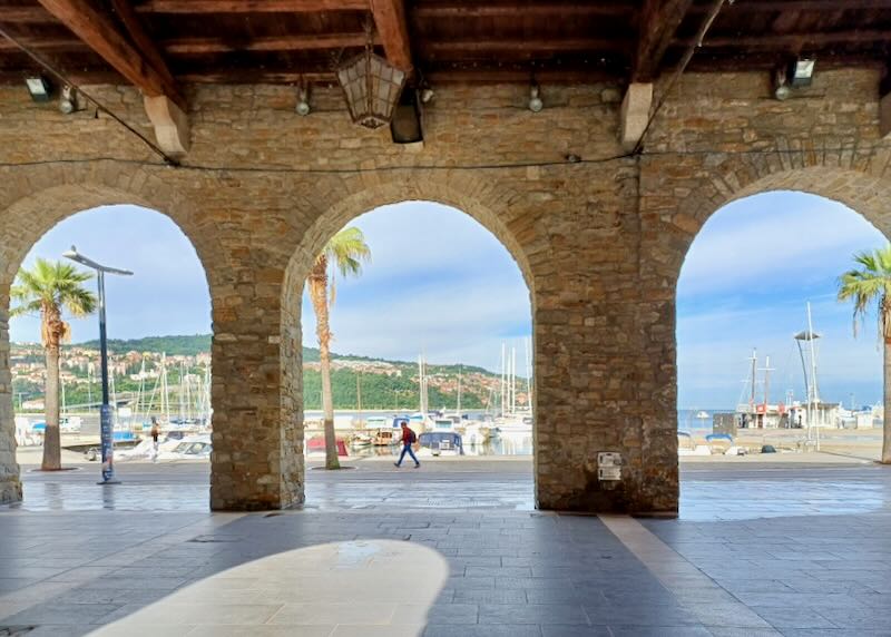 Stone archways present a view of a marina.