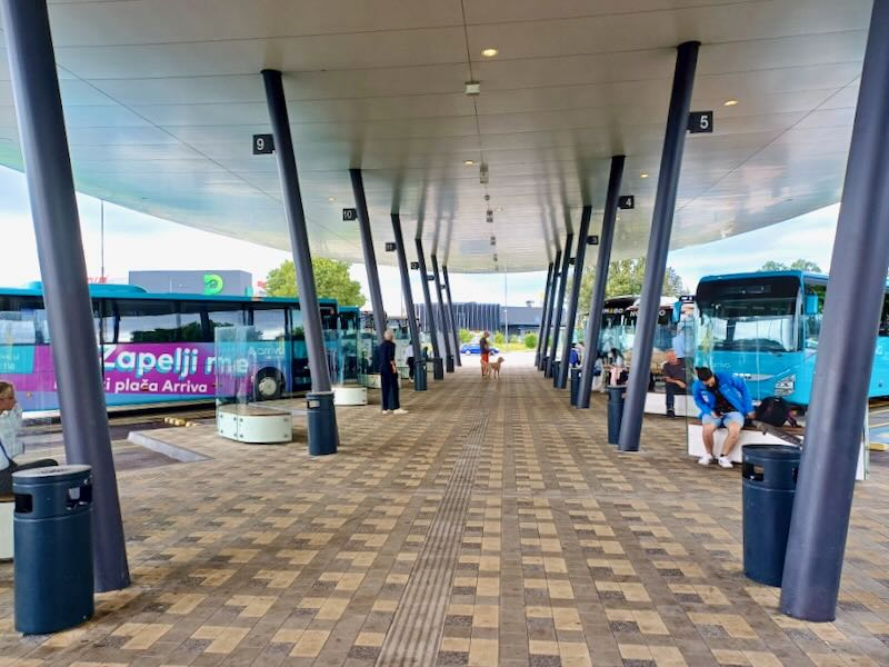 People sit waiting under a covered bus station.