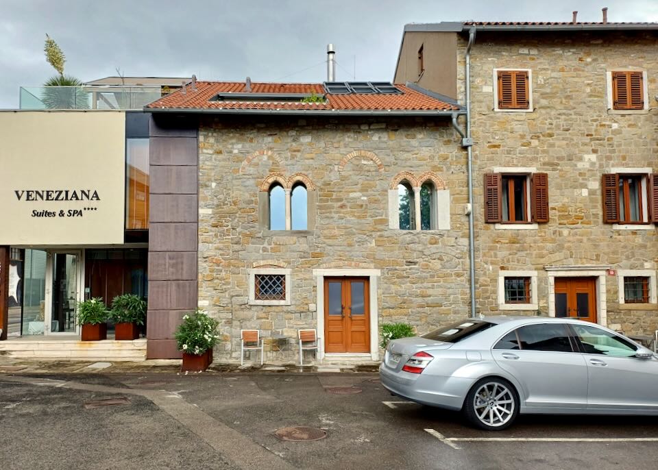 A car parks in front of a stone hotel.