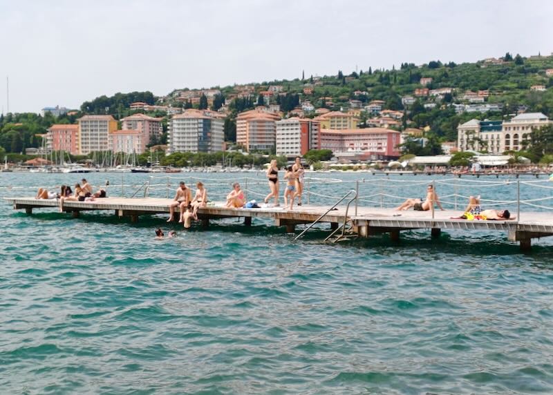 People sit on a pier and sunbathe.