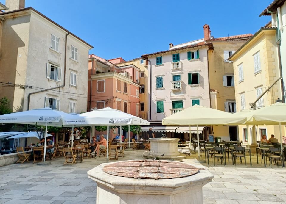A town square surrounded by pink, coral, and yellow buildings.