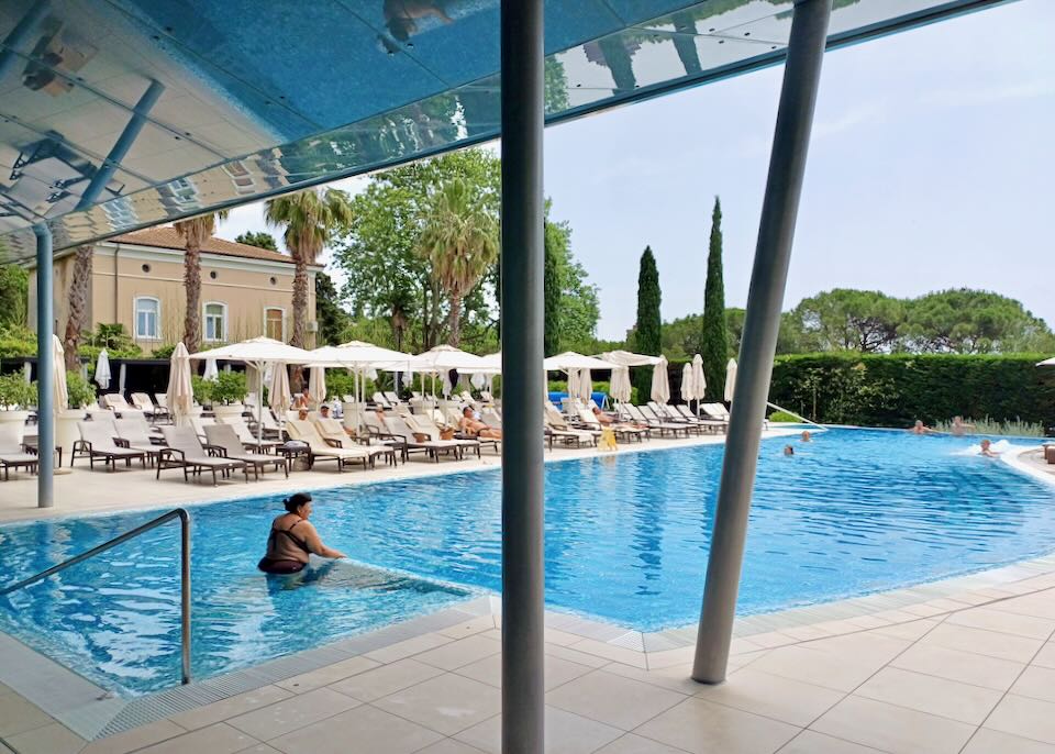 A woman wades into a large pool.