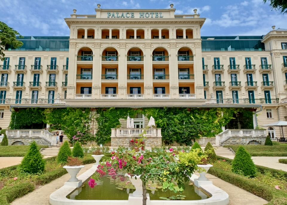 A grand historic hotel with many levels and lush gardens.