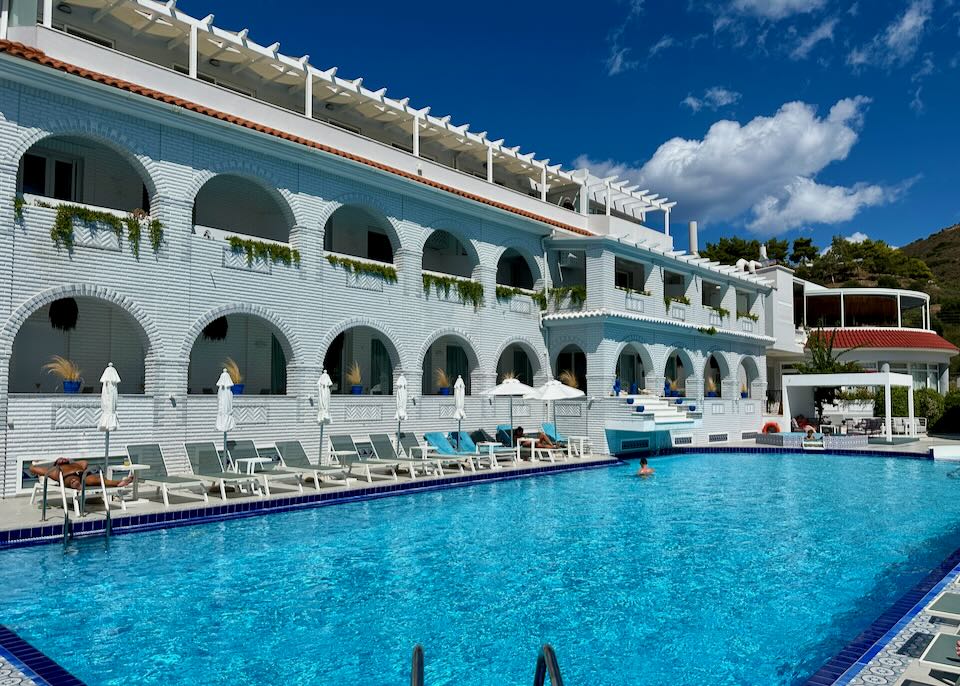 A man swims in a crystal blue hotel swimming pool on a sunny day.