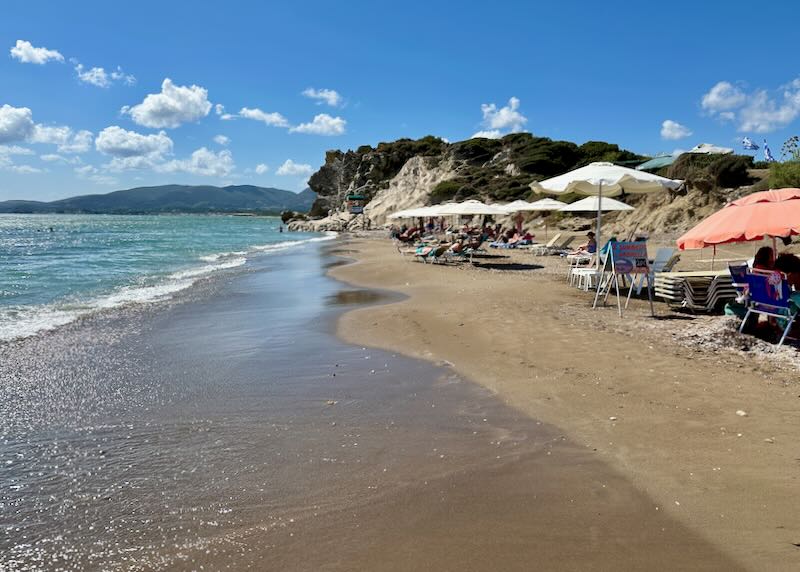 Beach with colorful sun umbrellas and a gentle wave rolling in to shore