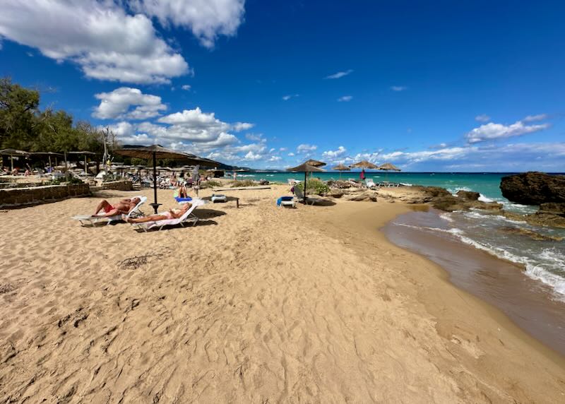 View up a sandy beach with thatched umbrellas on a sunny day