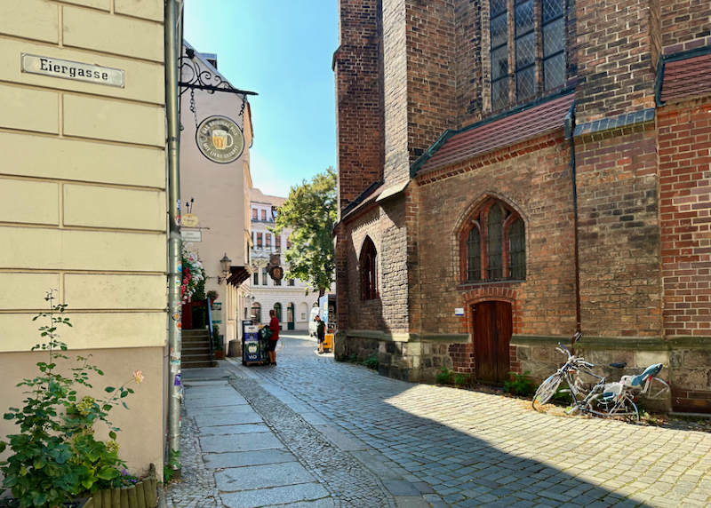 A quiet street in Nikolaiviertel, Berlin, with a bicycle resting against the side of a church building