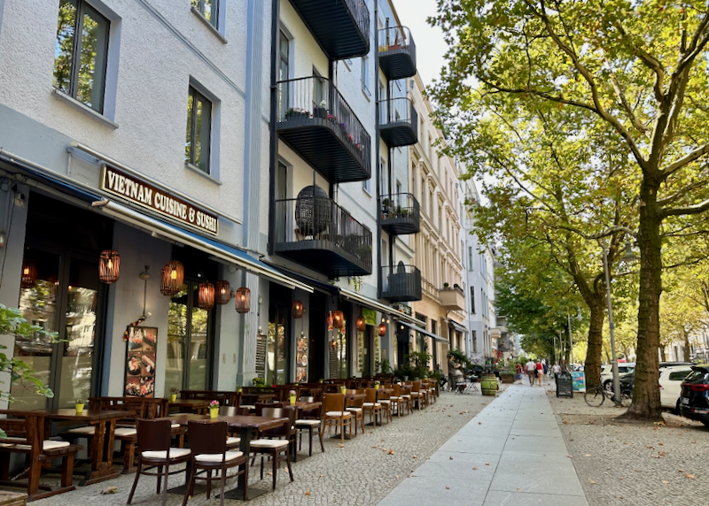 Sidewalk lined with cafes and leafy trees