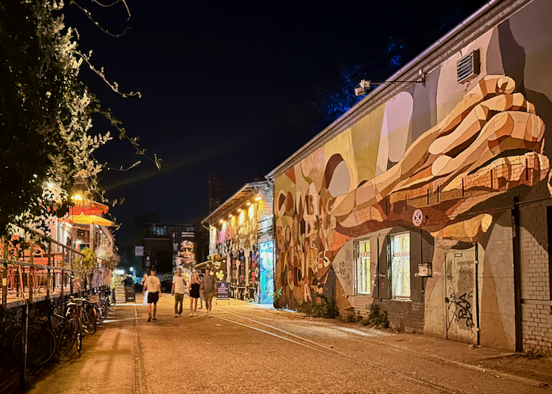 People walk down a grafitti-covered alley at night