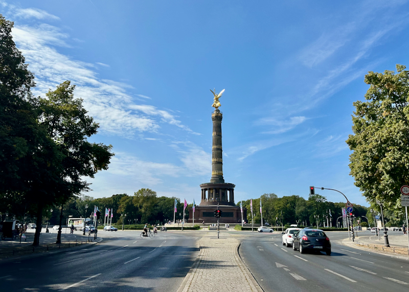 Large obelisk in a roadway roundabout, with a golden winged figure perched on top