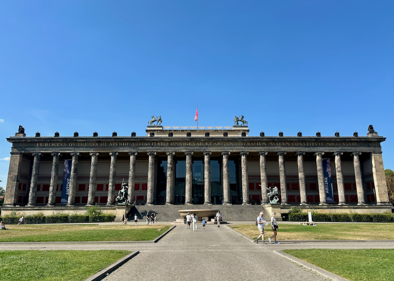 Massive long colonnaded building with a green plaza in front