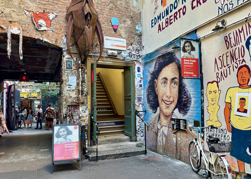 Grafitti-covered alley with mural of Anne Frank
