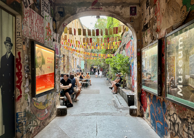 Grafitti covered passageway leading to a leafy courtyard