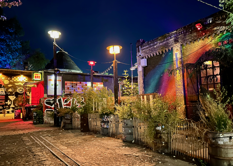 Colorful grafitti-covered buildings, lit by string lights at night