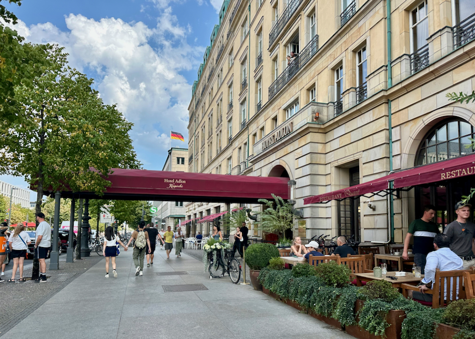 A couple walks hand in hand past the entrance awning of a luxury hotel in Berlin