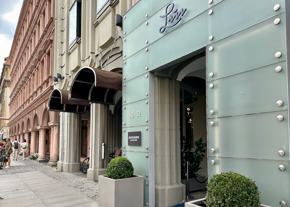 View Looking down a sidewalk past the entrance of a modern luxury hotel